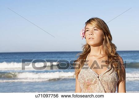 Young woman in summer dress, standing in front of sea, flower in hair View Large Photo Image Stock Photograph - Young woman in summer dress, standing in front of sea, flower in hair. Fotosearch