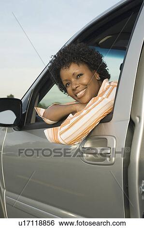 Stock Photograph - Young woman looking through car window. Fotosearch