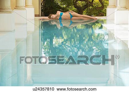 Young woman lying by swimming pool, portrait View Large Photo Image Stock Image - Young woman lying by swimming pool, portrait. Fotosearch