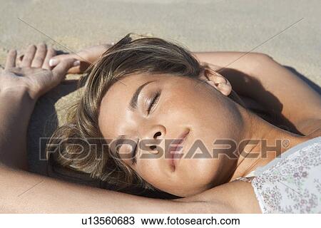 Stock Image - Young woman lying on beach, close-up. Fotosearch
