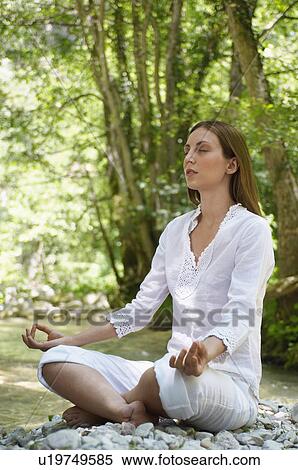 Young woman meditating by forest river, full length View Large Photo Image Stock Photography - Young woman meditating by forest river, full length. Fotosearch