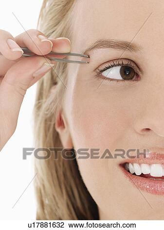 Stock Image - Young Woman plucking Eyebrow, close up, cropped. Fotosearch