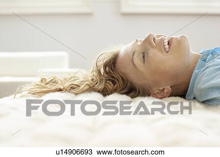 Young woman relaxing on bed, portrait View Large Photo Image Stock Image - Young woman relaxing on bed, portrait. Fotosearch