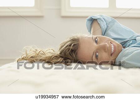 Young woman relaxing on bed, portrait View Large Photo Image Stock Photo - Young woman relaxing on bed, portrait. Fotosearch