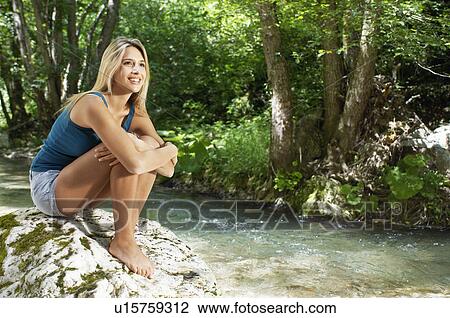 Young woman sitting by river in forest View Large Photo Image Stock Image - Young woman sitting by river in forest. Fotosearch