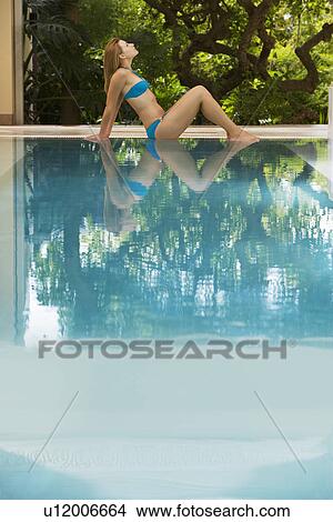 Young woman sitting by swimming pool, portrait, side view View Large Photo Image Picture - Young woman sitting by swimming pool, portrait, side view. Fotosearch