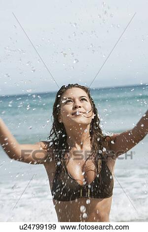 Stock Photo - Young Woman Splashing in Surf at Beach. Fotosearch