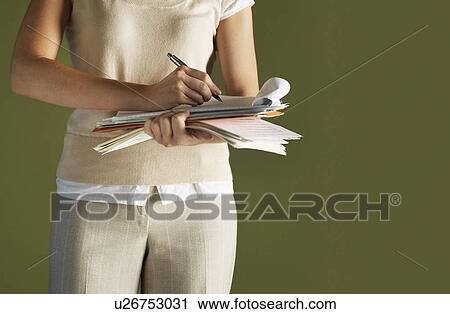 Young woman standing, holding notepad, writing, mid section View Large Photo Image Stock Image - Young woman standing, holding notepad, writing, mid section. Fotosearch