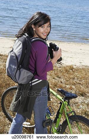 Young woman standing with mountain bike using binoculars by lake View Large Photo Image Stock Image - Young woman standing with mountain bike using binoculars by lake. Fotosearch