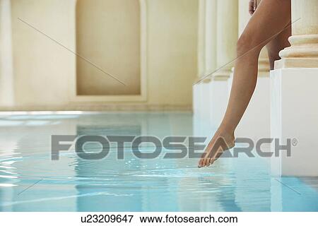 Stock Photo - Young woman stepping into swimming pool, low section. Fotosearch