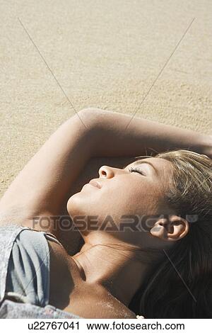 Stock Image - Young Woman Sunbathing on Beach. Fotosearch