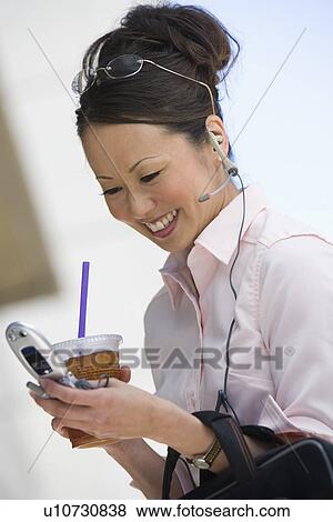 Stock Photo - Young woman text messaging holding drink. Fotosearch