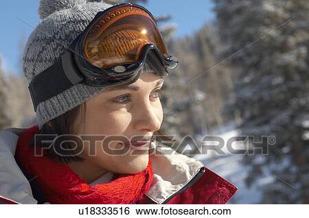 Young woman wearing ski goggles on head 
