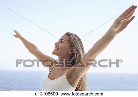 Young woman with arms outstretched on beach View Large Photo Image Stock Image - Young woman with arms outstretched on beach. Fotosearch