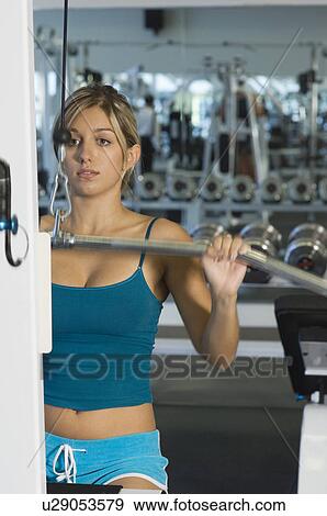 Stock Photo - Young Woman Working Out on Weightlifting Machine. Fotosearch