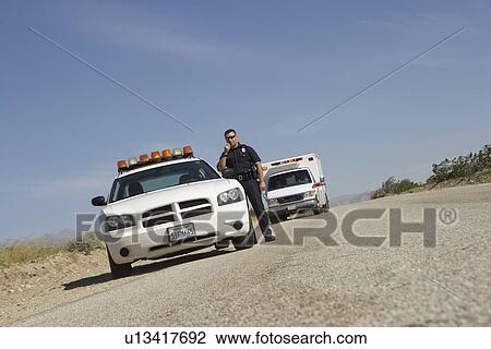 ضابط شرطة تصنيف بجانب سيارة الشرطة ب سيارة إسعاف إلى داخل الخلفية ألبوم الصور U13417692 Fotosearch