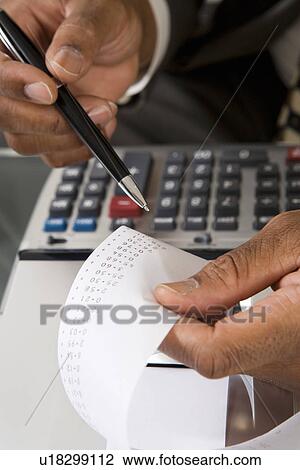 Stock Image - Accountant Reading Adding Machine Tape. Fotosearch