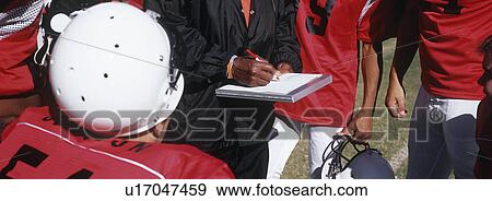 Stock Photo - American football team with coach, mid section. Fotosearch