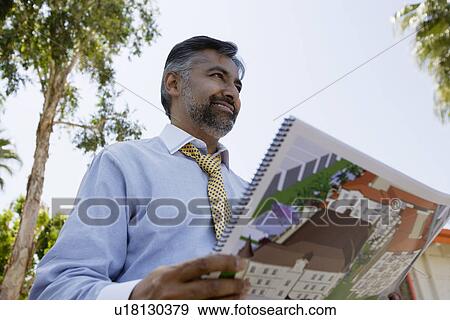 Stock Photo - Architect Holding Book with Building Plans. Fotosearch