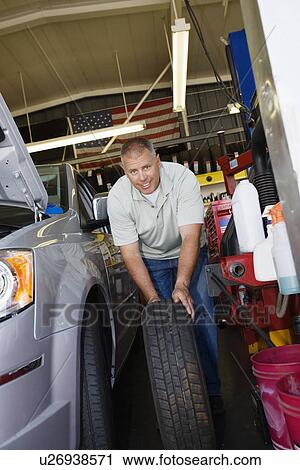 Stock Image - Auto Mechanic Changing a Tire. Fotosearch