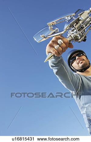 Stock Image - Biker riding motorcycle, low angle view. Fotosearch