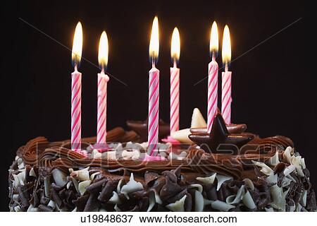 Stock Photo - Birthday cake with lit candles, close-up. Fotosearch