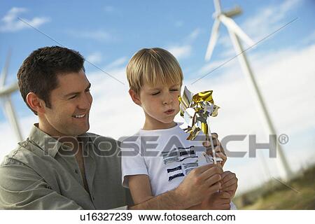 Boy (7-9) blowing toy windmill with father at wind farm View Large Photo Image Stock Photo - Boy (7-9) blowing toy windmill with father at wind farm. Fotosearch