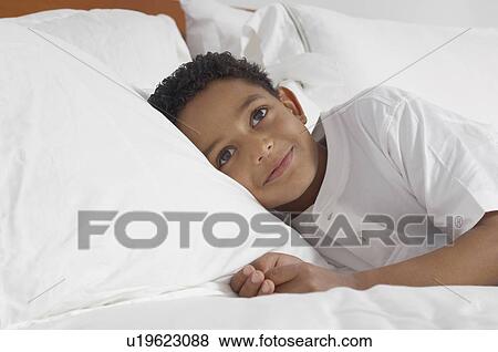 Boy (7-9) lying in bed smiling, portrait View Large Photo Image Stock Photo - Boy (7-9) lying in bed smiling, portrait. Fotosearch
