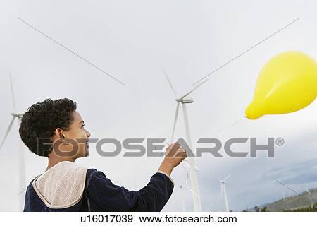 Boy (7-9) playing with balloon at wind farm View Large Photo Image Stock Photo - Boy (7-9) playing with balloon at wind farm. Fotosearch
