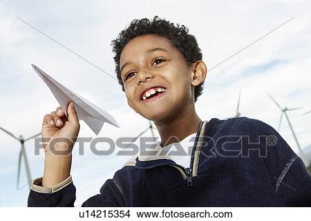 Picture - Boy (7-9) playing with paper plane at wind farm. Fotosearch