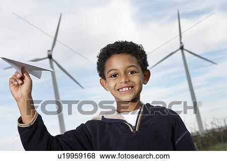 Boy (7-9) playing with paper plane at wind farm, portrait View Large Photo Image Stock Photo - Boy (7-9) playing with paper plane at wind farm, portrait. Fotosearch