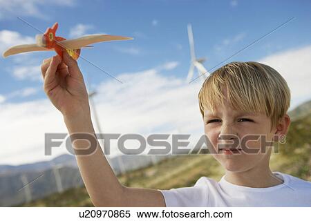 Boy (7-9) playing with toy glider at wind farm View Large Photo Image Stock Photography - Boy (7-9) playing with toy glider at wind farm. Fotosearch