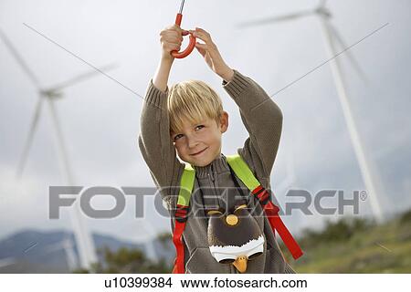 Boy (7-9) playing with umbrella at wind farm View Large Photo Image Picture - Boy (7-9) playing with umbrella at wind farm. Fotosearch
