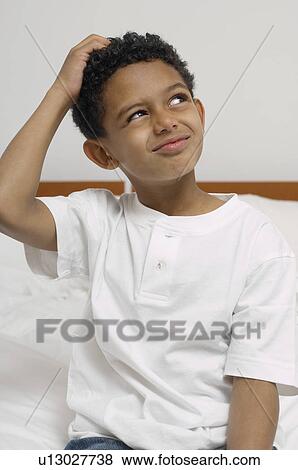 Stock Photo - Boy (7-9) with hand on head on bed. Fotosearch