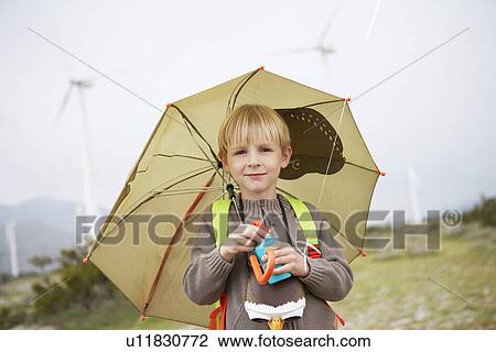 Boy (7-9) with umbrella at wind farm, portrait View Large Photo Image Stock Image - Boy (7-9) with umbrella at wind farm, portrait. Fotosearch