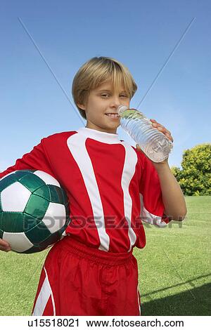 Boy (7-9 years) soccer player holding ball and water bottle, portrait View Large Photo Image Stock Image - Boy (7-9 years) soccer player holding ball and water bottle, portrait. Fotosearch