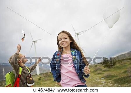 Boy and girl (5-9) playing with balloons at wind farm View Large Photo Image Stock Photo - Boy and girl (5-9) playing with balloons at wind farm. Fotosearch