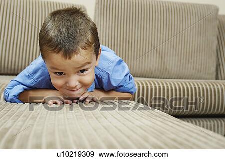 Boy relaxing on sofa in living room View Large Photo Image Stock Photo - Boy relaxing on sofa in living room. Fotosearch