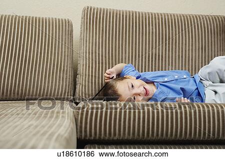 Stock Photograph - Boy relaxing on sofa in living room. Fotosearch