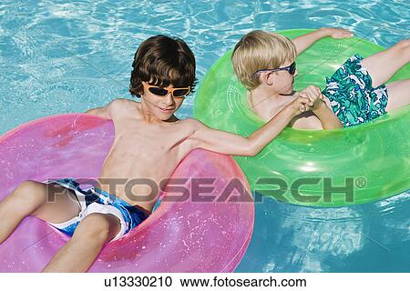Stock Image - Boys on Float Tubes in Swimming Pool. Fotosearch