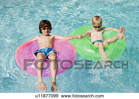 Boys on Float Tubes in Swimming Pool View Large Photo Image Stock Photo - Boys on Float Tubes in Swimming Pool. Fotosearch