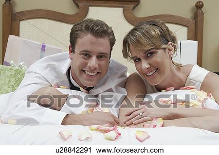 Bride and groom relaxing on bed among presents, portrait View Large Photo Image Stock Image - Bride and groom relaxing on bed among presents, portrait. Fotosearch
