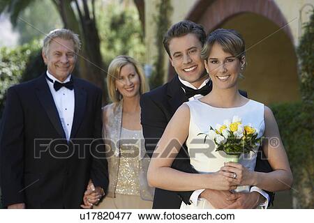 Stock Photo - Bride and groom with parents in background, portrait. Fotosearch