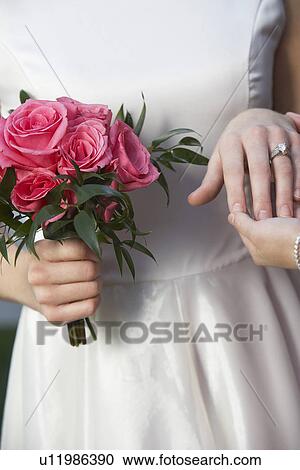 Bride holding bouquet and touching groom's hand, mid-section, close-up of hands View Large Photo Image Stock Image - Bride holding bouquet and touching groom's hand, mid-section, close-up of hands. Fotosearch