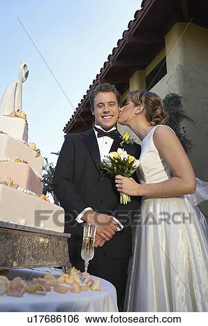 Bride kissing groom near wedding cake, portrait View Large Photo Image Stock Photograph - Bride kissing groom near wedding cake, portrait. Fotosearch