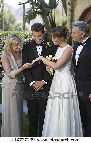Stock Photo - Bride showing ring to mother, groom and father looking on. Fotosearch