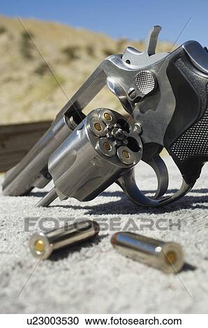 Stock Image - Bullets beside gun, close-up. Fotosearch