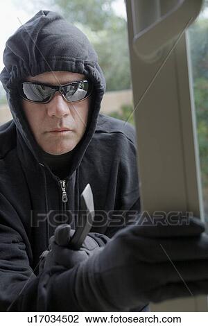 Stock Image - Burglar breaking into house. Fotosearch