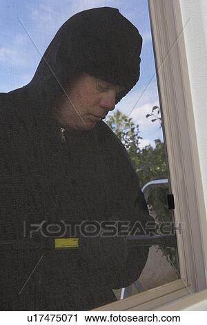 Stock Image - Burglar breaking into house. Fotosearch