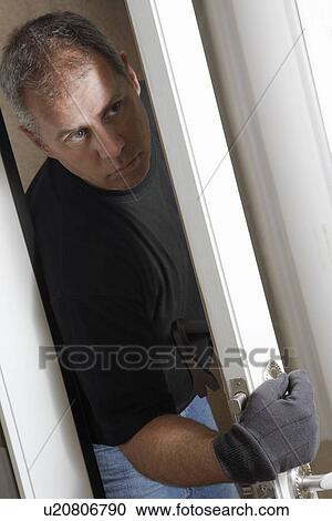 Stock Image - Burglar breaking into house. Fotosearch